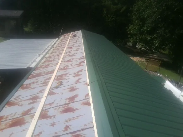 Old rusted panels beside newly installed green metal roofing — Wind Damage Roof Repair by Roofing Brothers in Middlebranch