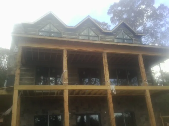 Dormers and porch framing on a large log home under construction — Roof Coating work by our crew in Middlebranch