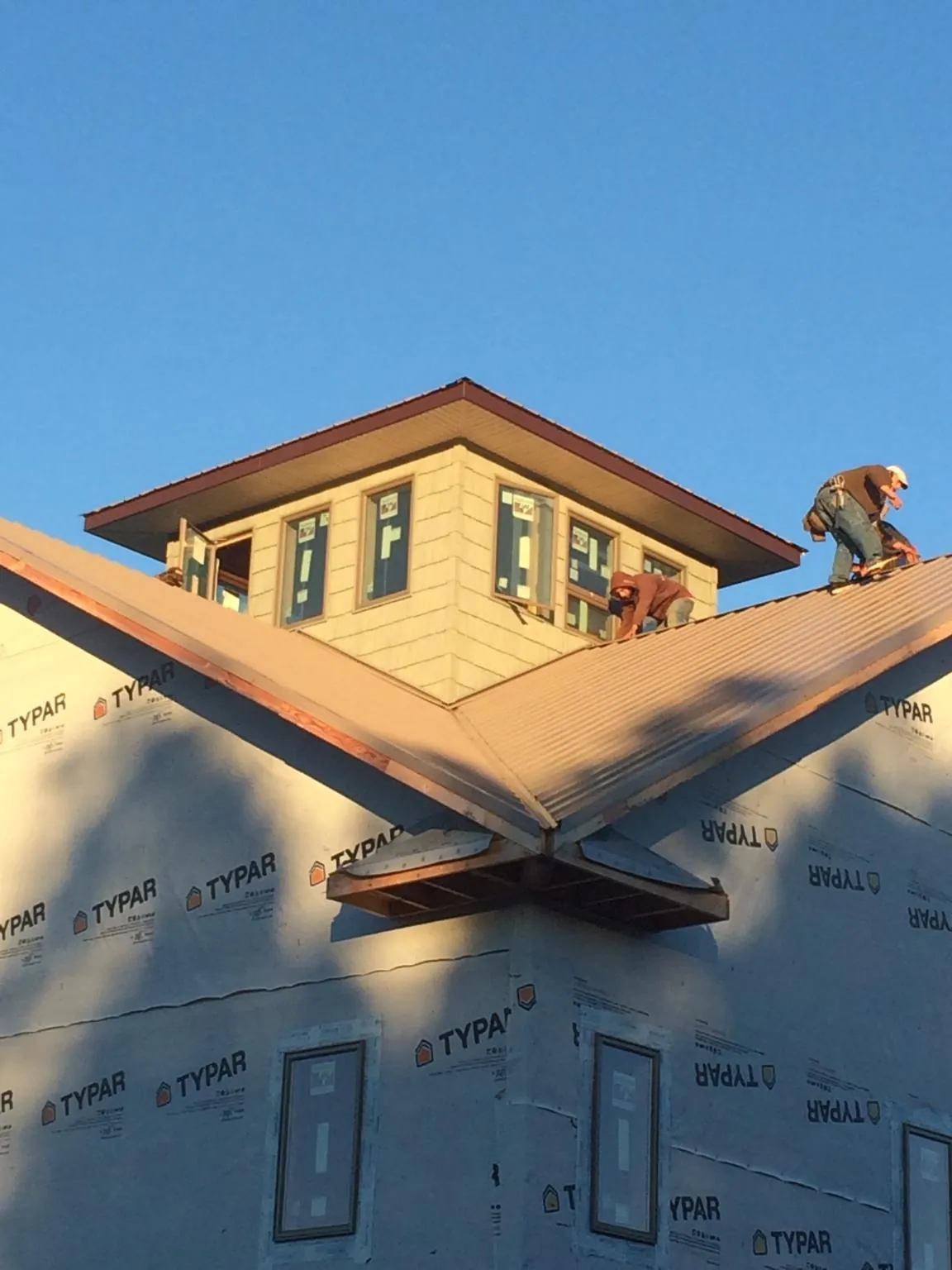 Roofers working around a rooftop cupola on a new metal roof at sunset — Roof Waterproofing in Middlebranch by Roofing Brothers